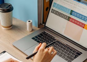 A person working on a laptop with documents and coffee in a modern workspace.